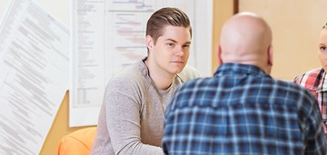 Kolme ihmistä pöydän ääressä, kuvituskuva.