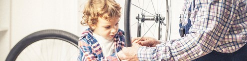 Aikuinen ja lapsi korjaavat polkupyörää, kuvituskuva.